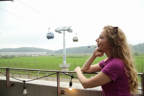 A woman having her photo taken in front of the DMZ Peace Gondola during a tour