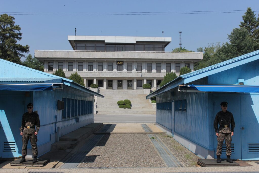 South Korean JSA Border Guards standing in front of the Military Demarcation Line with North Korea's Panmungak building in the background